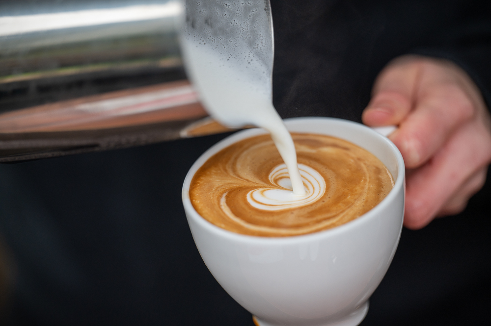 Ein Barista zeichnet Latte Art in einen Cappuccino.
